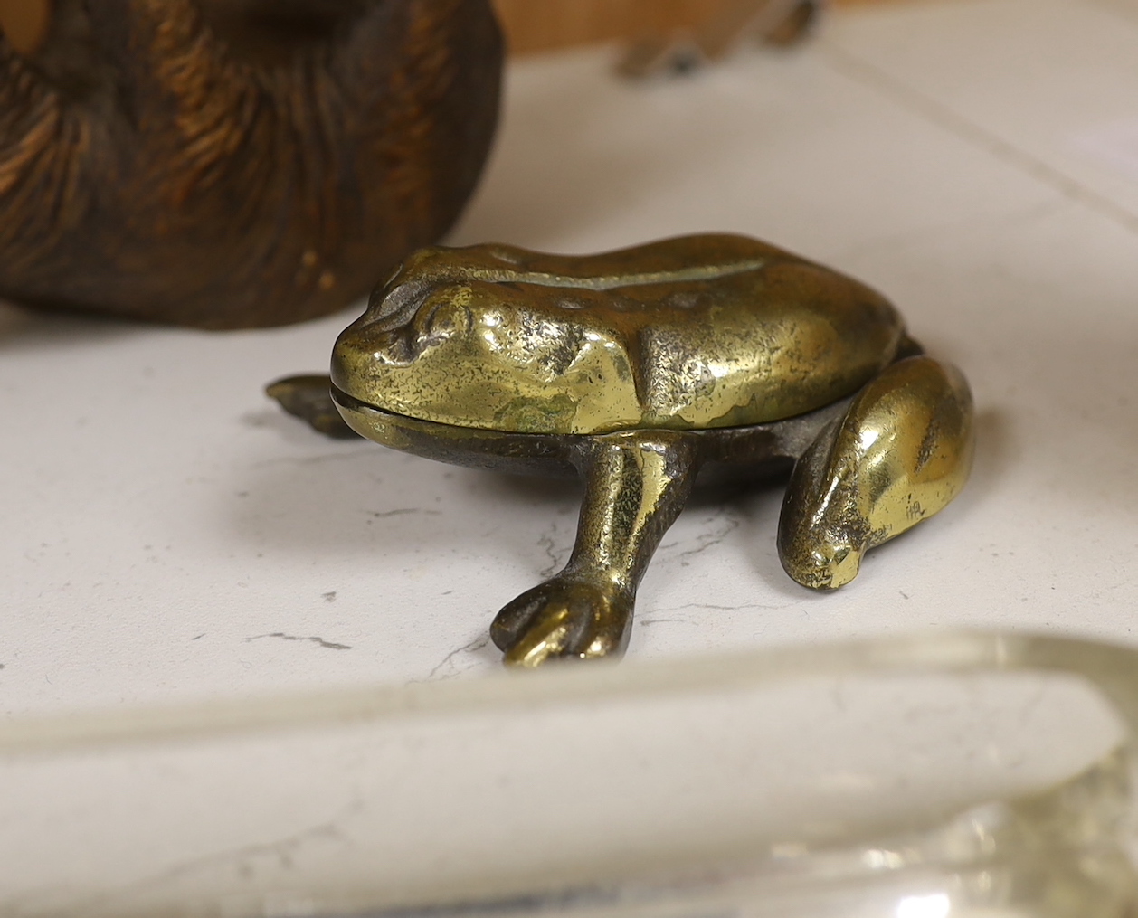 A resin Black Forest bear sculpture, a smaller Black Forest bear (possibly an ink stand but missing glass insert) together with a glass pen dish and brass hinged frog, the largest 25cm high